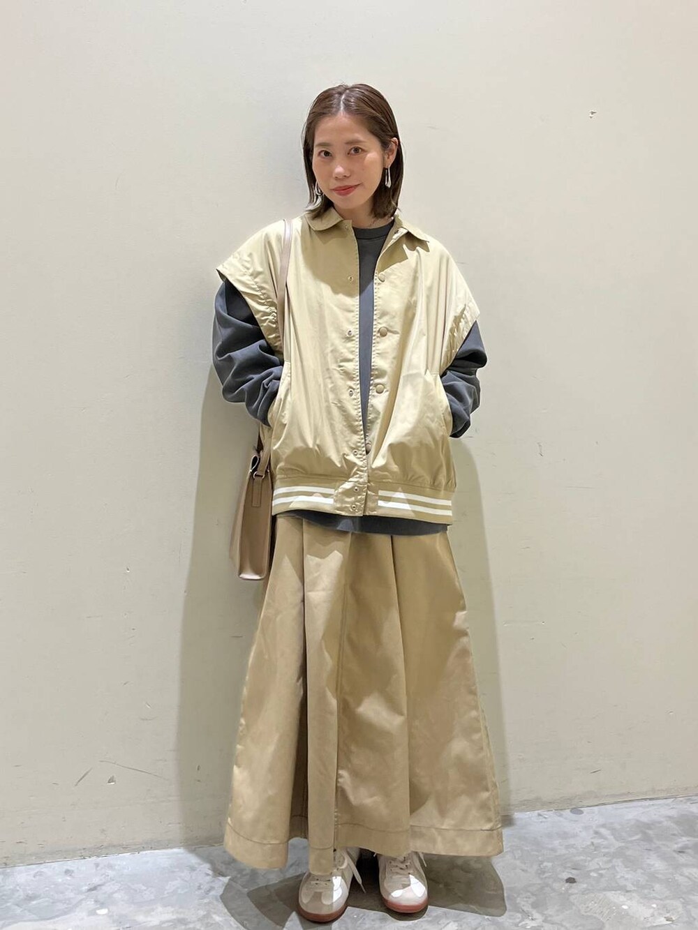 ベージュ系のスニーカー、ベージュ系のスタジャン、ベージュ系のスカートを着用したレディースの冬コーディネートの6枚目の写真