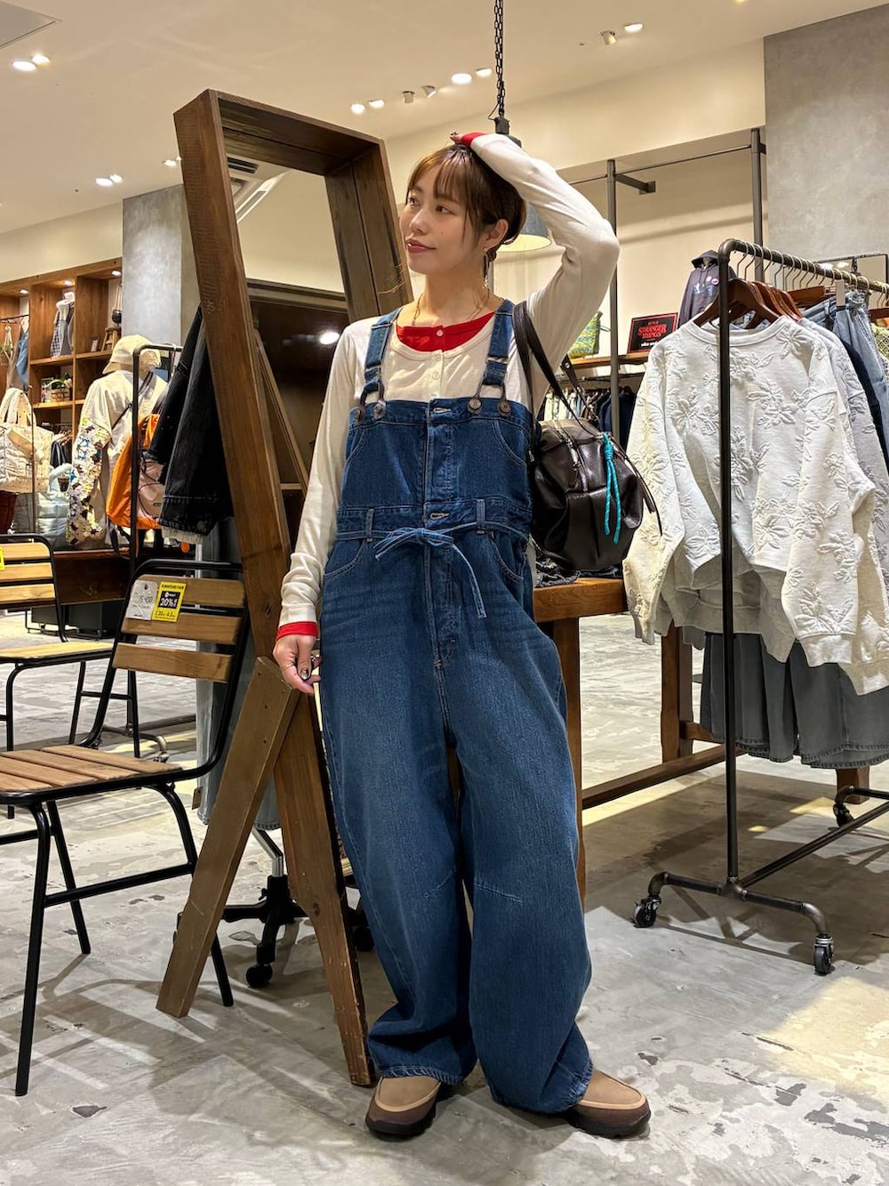 ブラウン系のボストンバッグ、ベージュ系のTシャツ/カットソー、ブルー系のサロペット/オーバーオールを着用したレディースの冬コーディネートの4枚目の写真