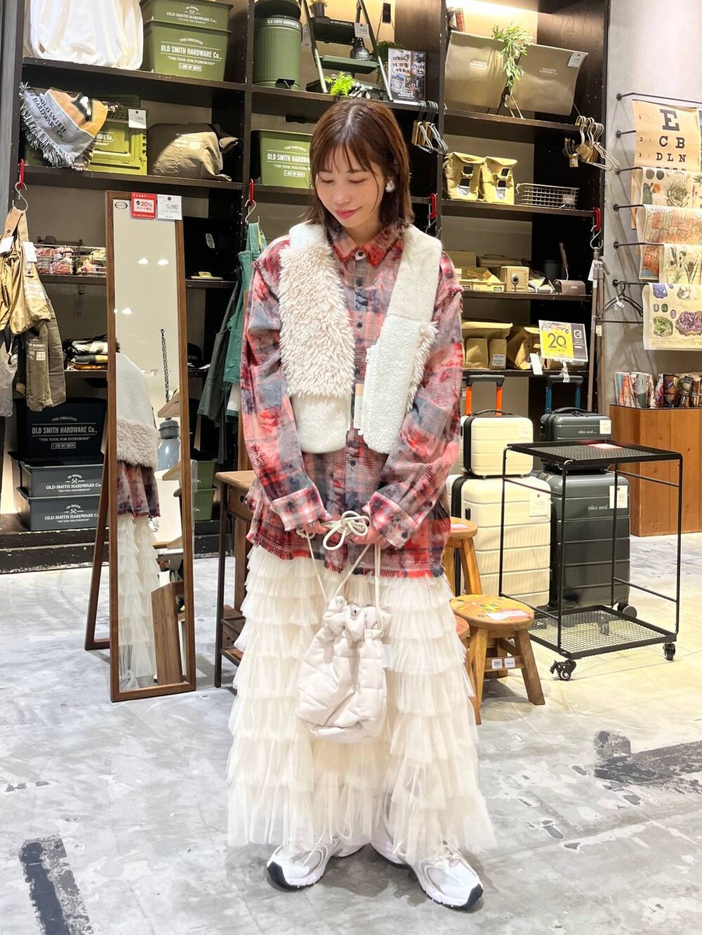ホワイト系のスニーカー、レッド系のシャツ/ブラウス、ベージュ系のベストを着用したレディースの秋コーディネートの2枚目の写真