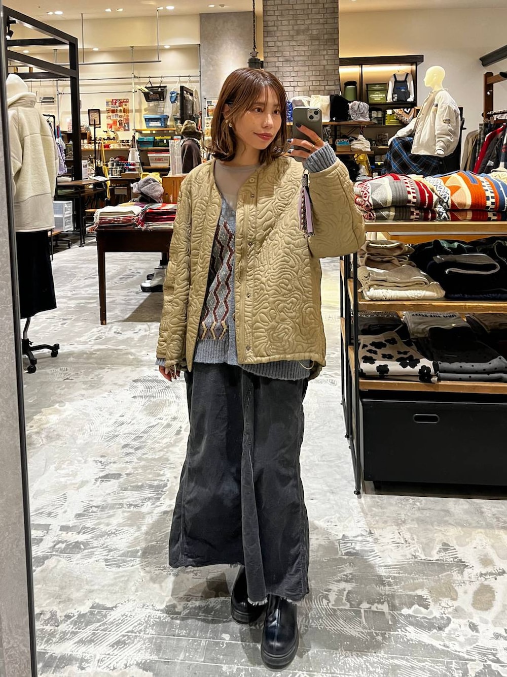 グレー系のスカート、ブルー系のカーディガン/ボレロ、ブラック系のブーツを着用したレディースの秋コーディネートの4枚目の写真