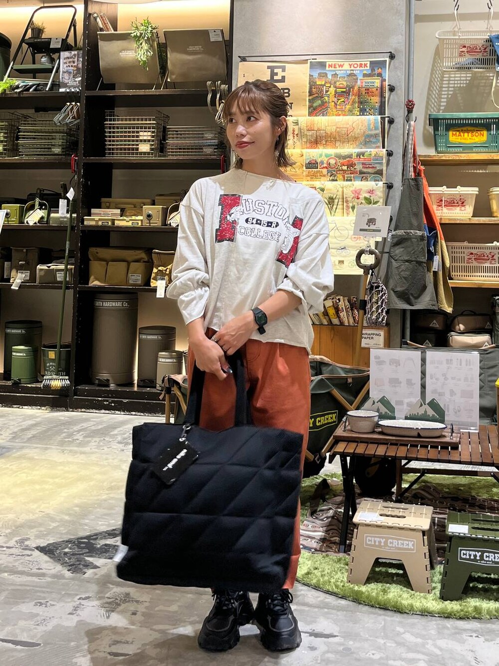 ブラック系のトートバッグ、オレンジ系のその他パンツ、ホワイト系のTシャツ/カットソーを着用したレディースの秋コーディネートの3枚目の写真