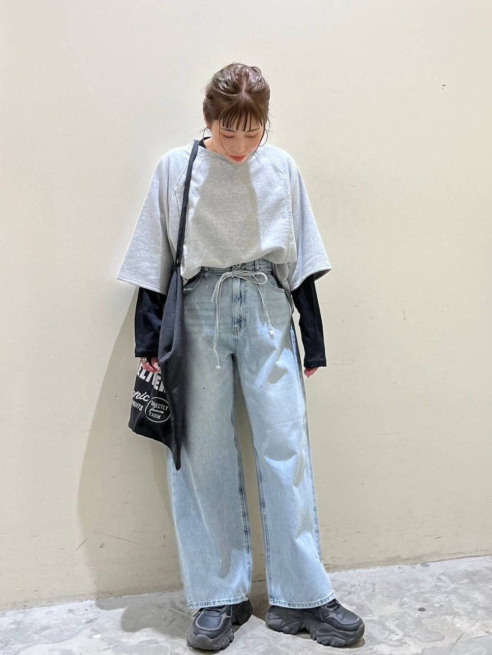 グレー系のトートバッグ、グレー系のTシャツ/カットソー、ブルー系のデニムパンツを着用したレディースの春コーディネートの2枚目の写真