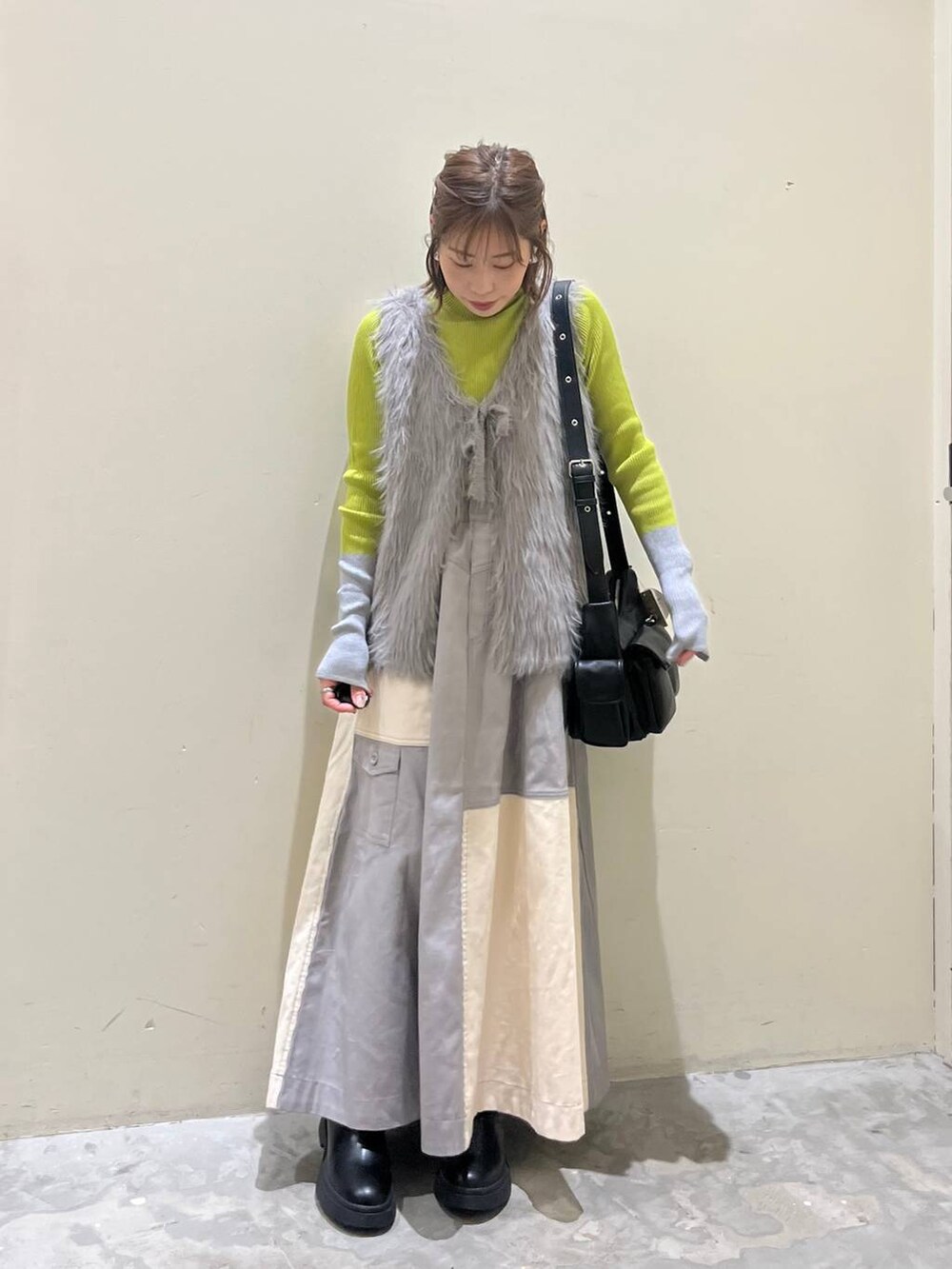 グリーン系のニット/セーター、ブラック系のブーツ、ブラック系のショルダーバッグを着用したレディースの冬コーディネートの8枚目の写真