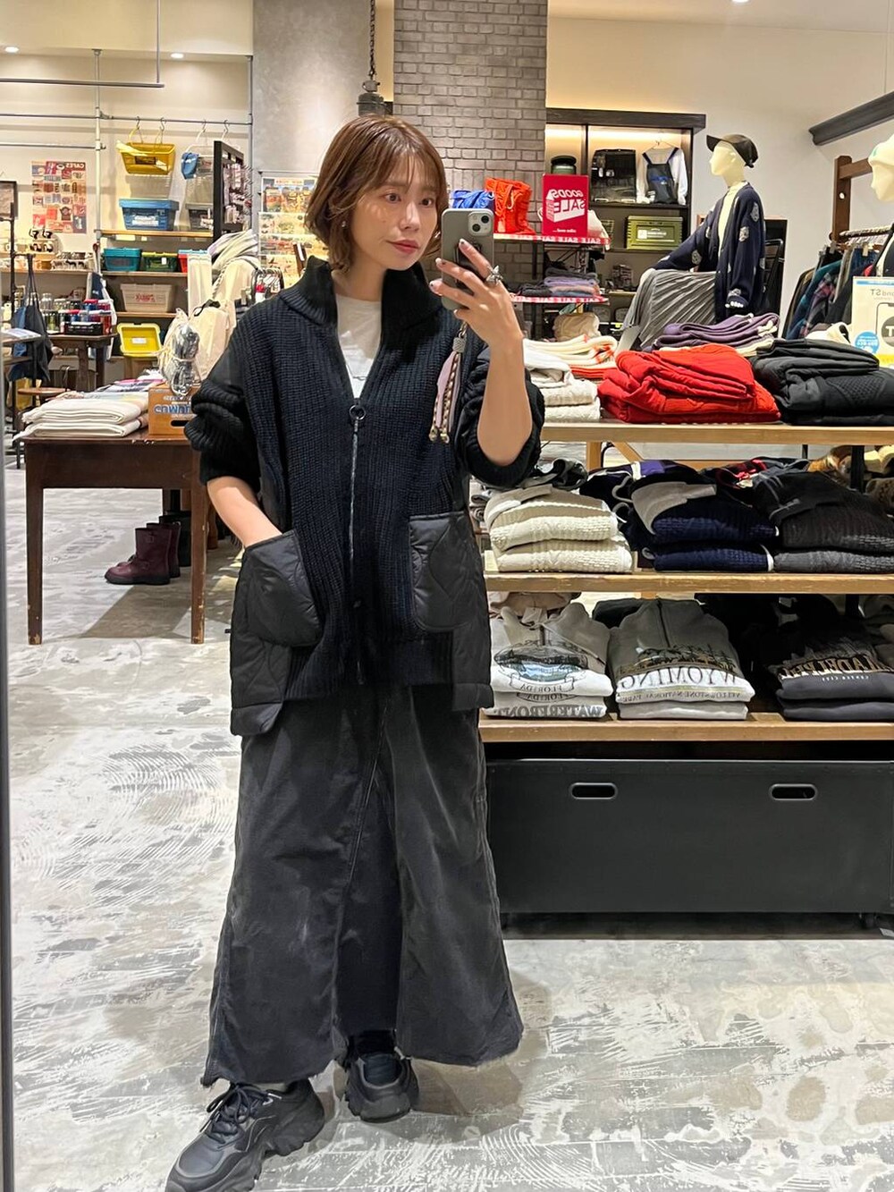 グレー系のスカート、グレー系のTシャツ/カットソー、ブラック系のブルゾンを着用したレディースの冬コーディネートの2枚目の写真