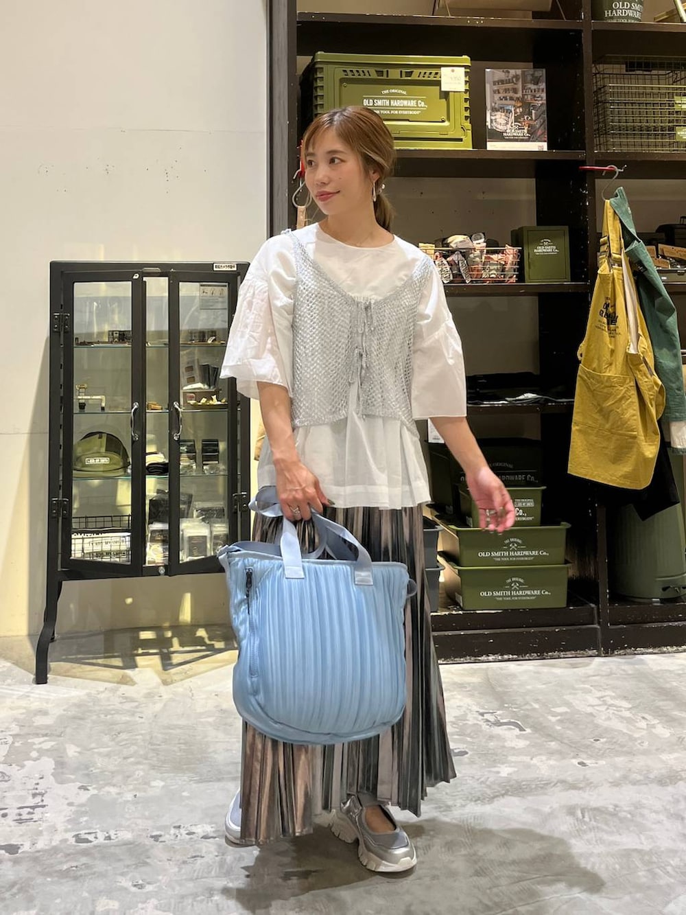 グレー系のスカート、ブルー系のトートバッグ、シルバー系のスニーカーを着用したレディースの夏コーディネートの6枚目の写真