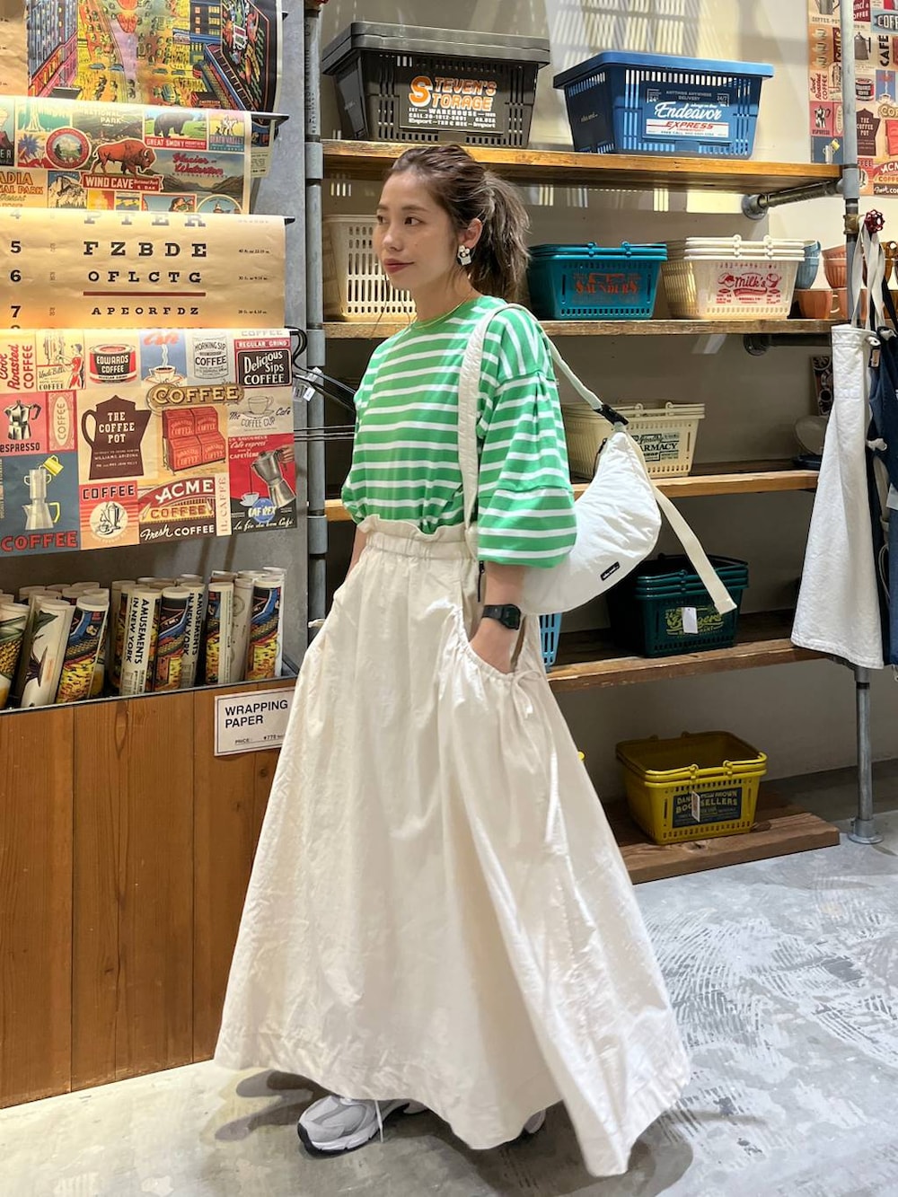 ベージュ系のスカート、ホワイト系のショルダーバッグ、グリーン系のTシャツ/カットソーを着用したレディースの春コーディネートの2枚目の写真