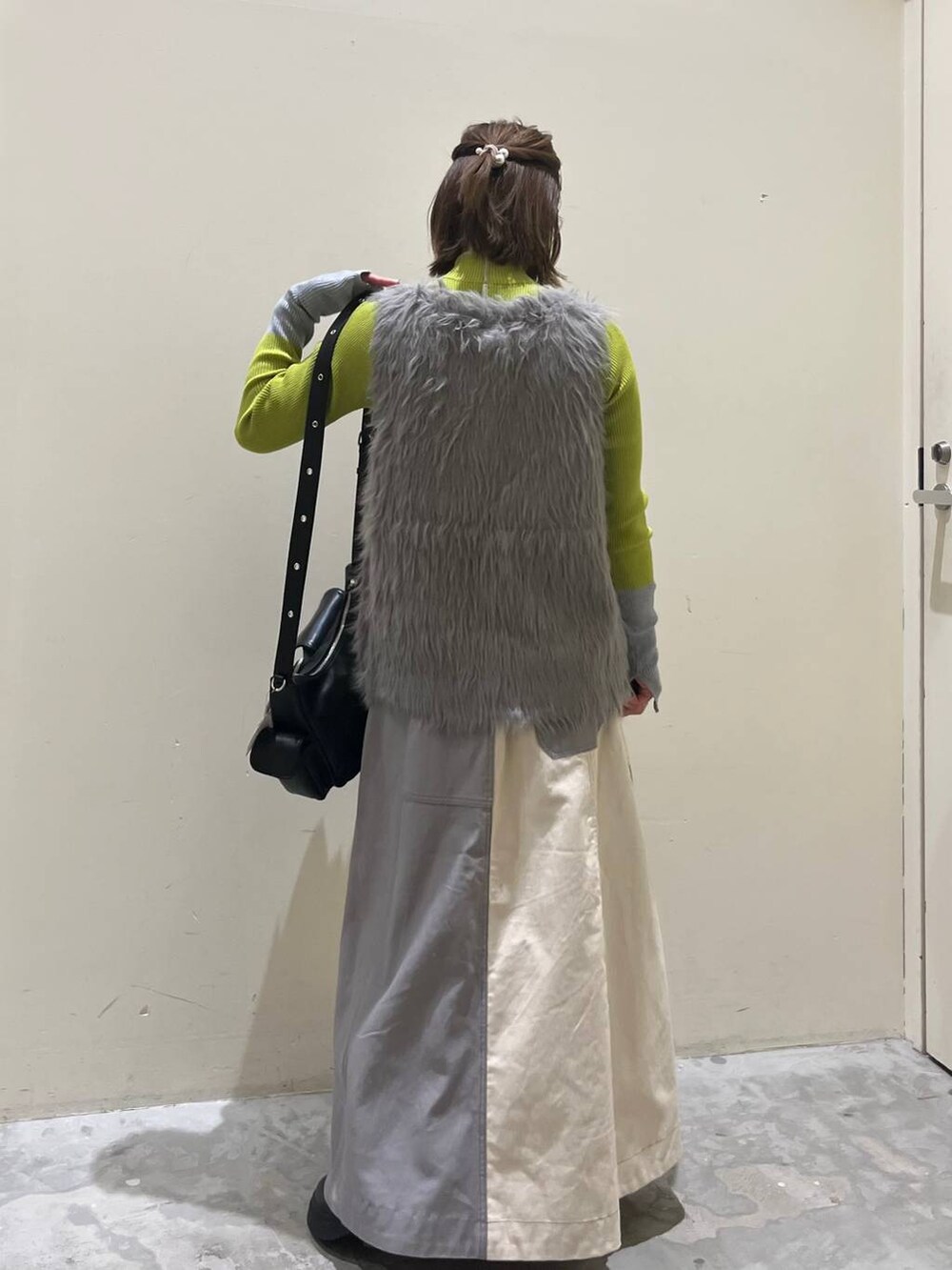 グリーン系のニット/セーター、ブラック系のブーツ、ブラック系のショルダーバッグを着用したレディースの冬コーディネートの3枚目の写真