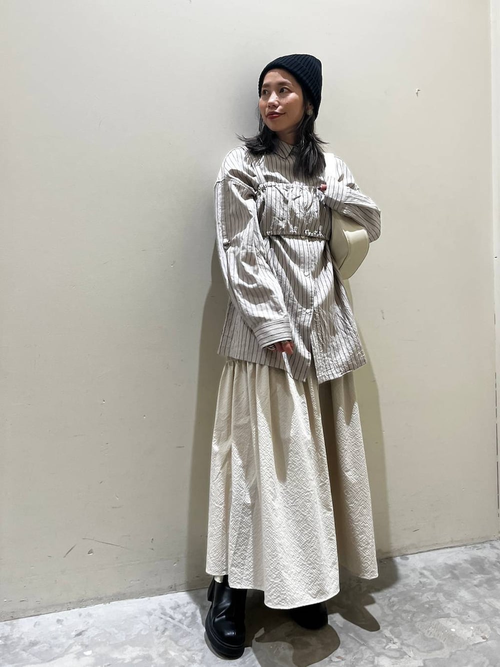 ベージュ系のショルダーバッグ、ブラック系のブーツ、ベージュ系のシャツ/ブラウスを着用したレディースの春コーディネートの2枚目の写真