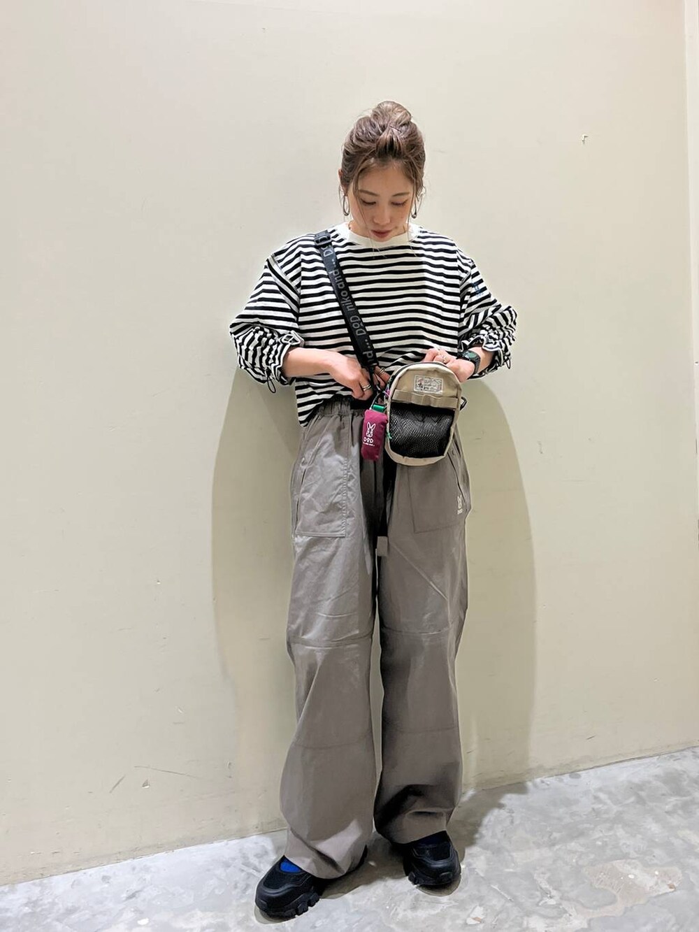 グレー系のその他パンツ、ブラック系のスニーカー、ホワイト系のTシャツ/カットソーを着用したレディースの春コーディネートの3枚目の写真