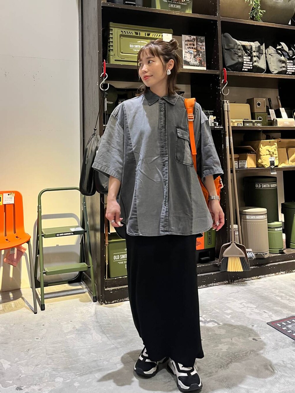 ブラック系のスカート、ブラック系のスニーカー、オレンジ系のバックパック/リュックを着用したレディースの春コーディネートの4枚目の写真