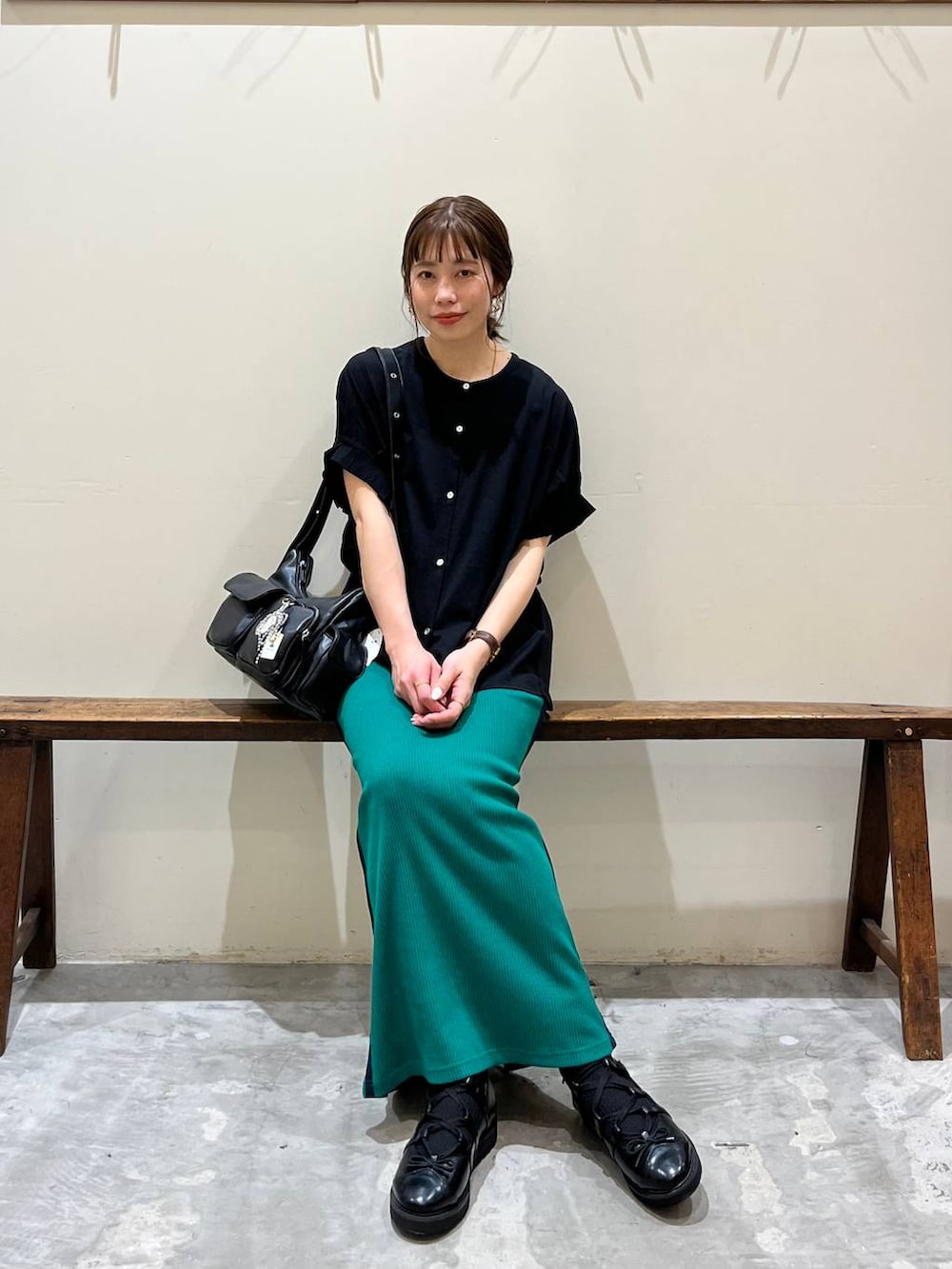 グリーン系のスカート、ブラック系のショルダーバッグ、ブラック系のバレエシューズを着用したレディースの春コーディネートの2枚目の写真