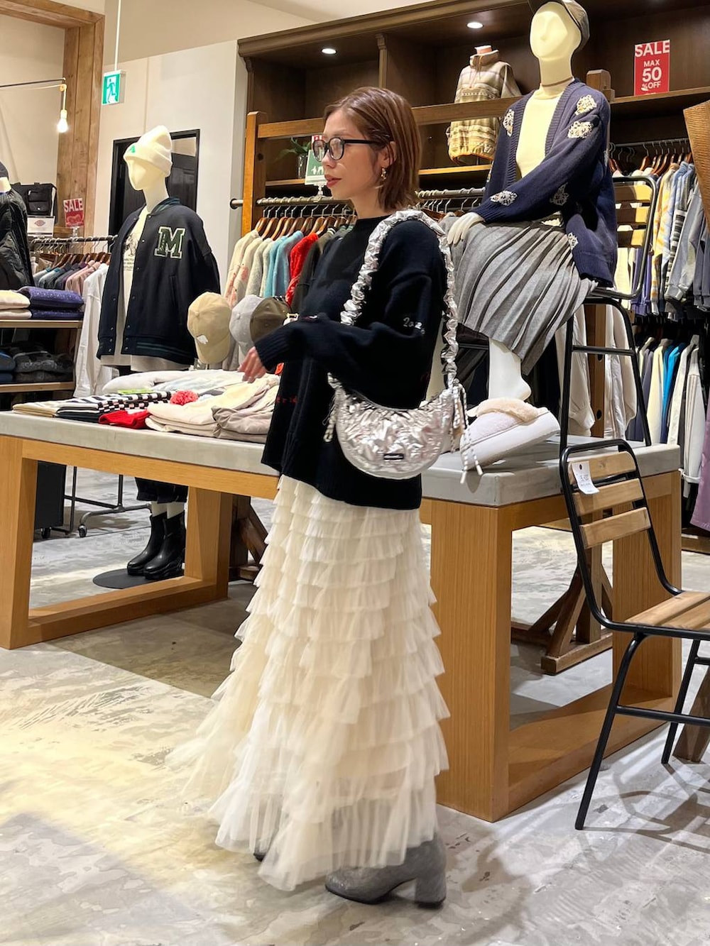 グレー系のブーツ、ホワイト系のスカート、シルバー系のショルダーバッグを着用したレディースの冬コーディネートの7枚目の写真