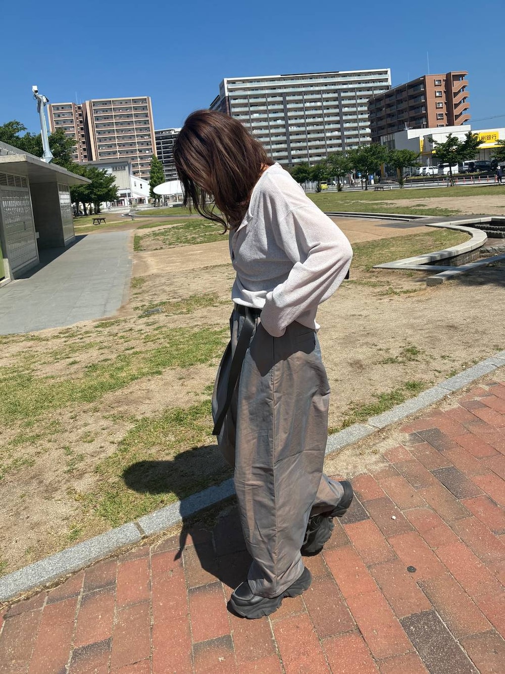 ブラック系のハンドバッグ、グレー系のTシャツ/カットソー、グリーン系のチノパンツを着用したレディースの夏コーディネートの2枚目の写真