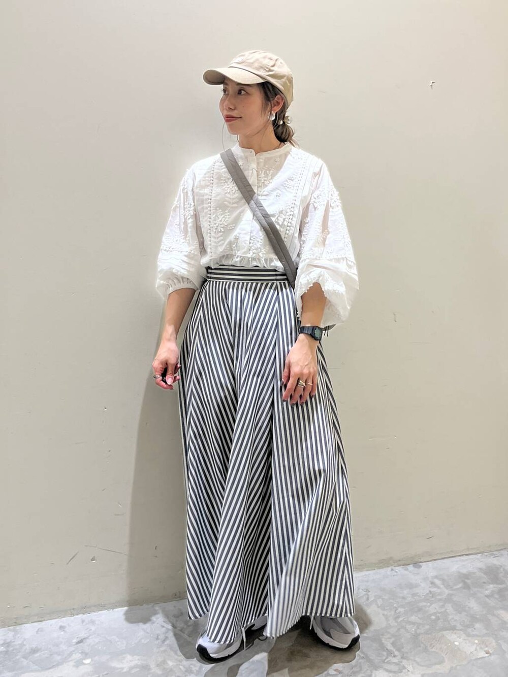 グレー系のショルダーバッグ、グレー系のスニーカー、ブルー系のスカートを着用したレディースの春コーディネートの3枚目の写真