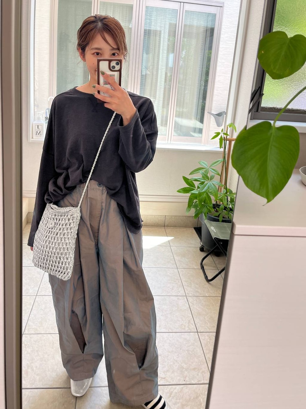 グレー系のショルダーバッグ、シルバー系のパンプス、グリーン系のチノパンツを着用したレディースの夏コーディネートの5枚目の写真