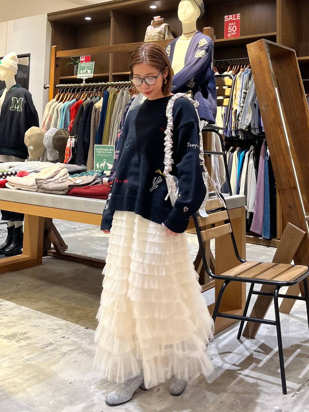 グレー系のブーツ、ホワイト系のスカート、シルバー系のショルダーバッグを着用したレディースの冬コーディネートの9枚目の写真