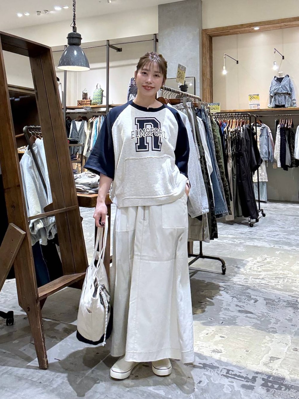 ベージュ系のトートバッグ、ベージュ系のTシャツ/カットソー、ベージュ系のスカートを着用したレディースの春コーディネートの5枚目の写真