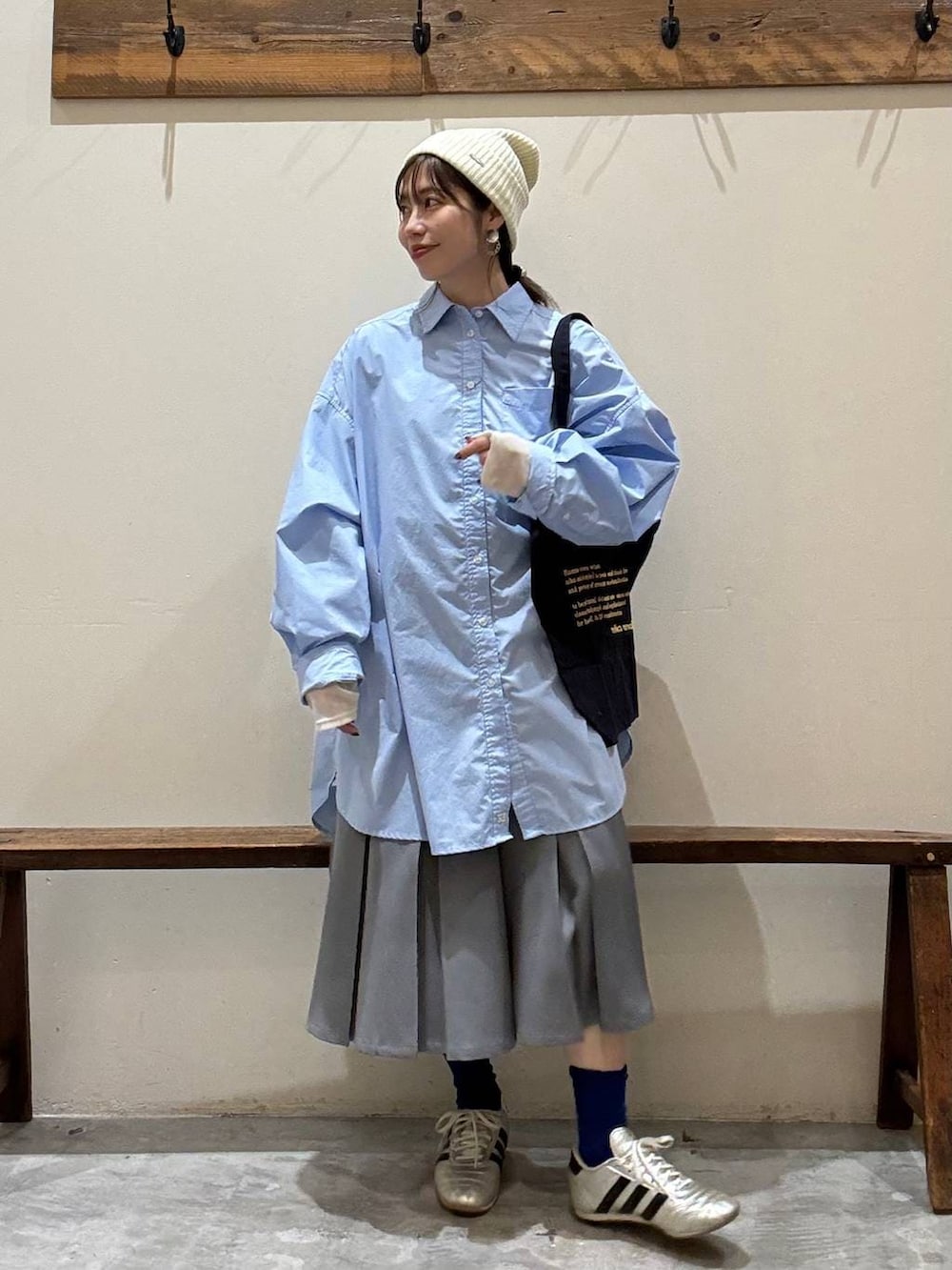 ブルー系のトートバッグ、ゴールド系のスニーカー、ベージュ系のTシャツ/カットソーを着用したレディースの冬コーディネートの2枚目の写真