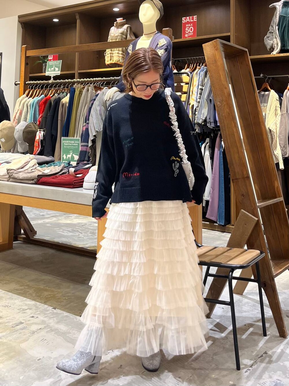 グレー系のブーツ、ホワイト系のスカート、シルバー系のショルダーバッグを着用したレディースの冬コーディネートの6枚目の写真