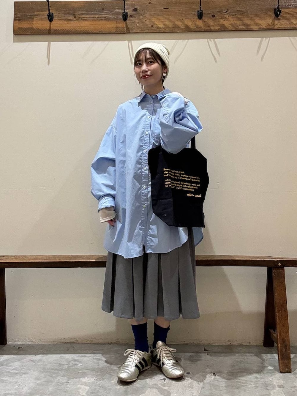 ブルー系のトートバッグ、ゴールド系のスニーカー、ベージュ系のTシャツ/カットソーを着用したレディースの冬コーディネートの4枚目の写真