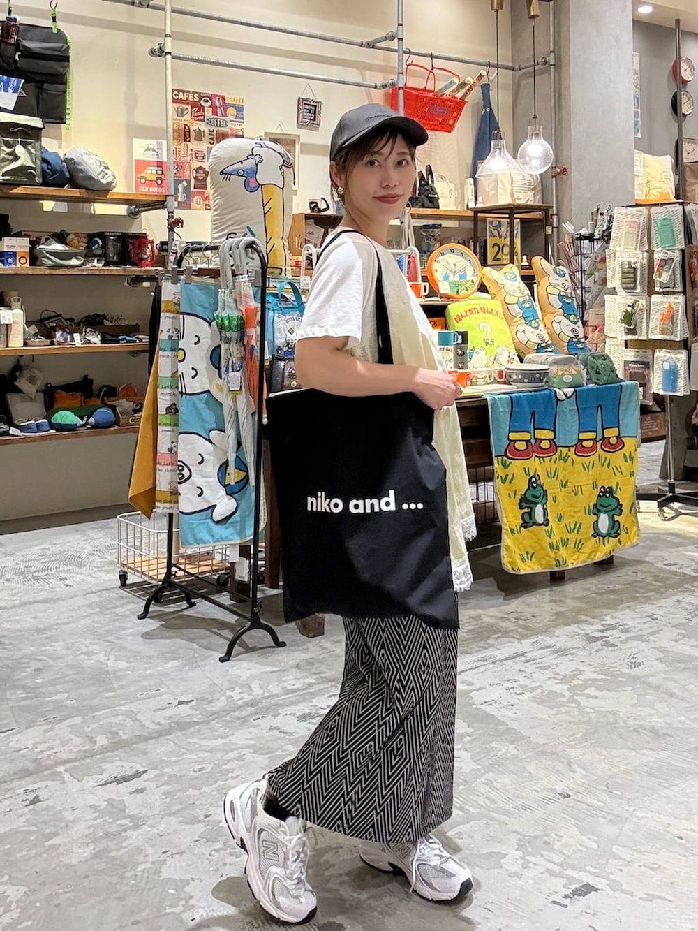 ブラック系のトートバッグ、ブラック系のスカート、ベージュ系のTシャツ/カットソーを着用したレディースの春コーディネートの3枚目の写真