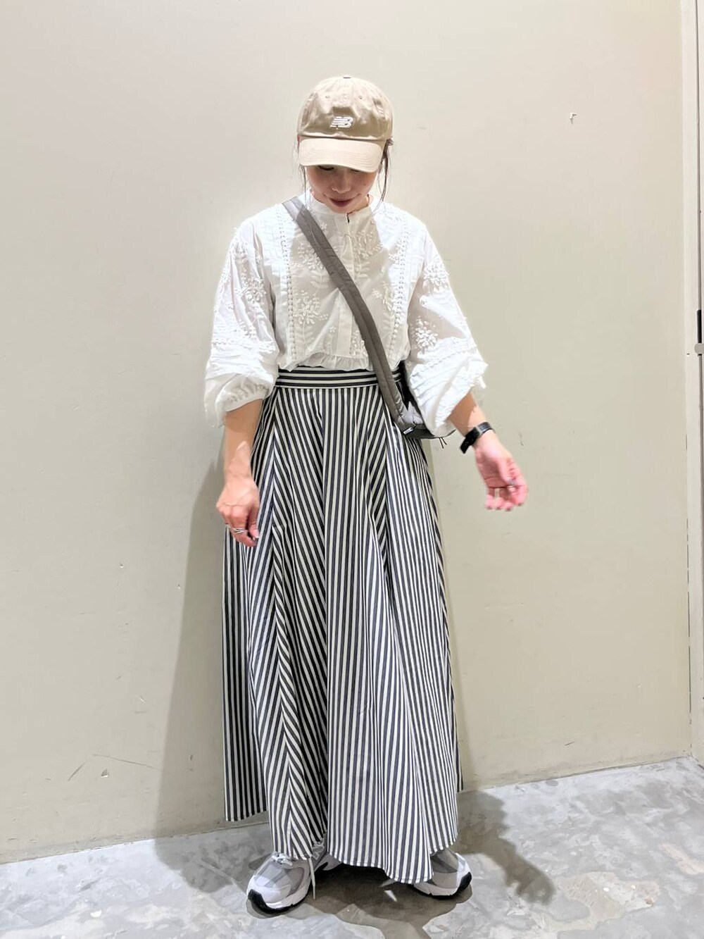 グレー系のショルダーバッグ、グレー系のスニーカー、ブルー系のスカートを着用したレディースの春コーディネートの2枚目の写真