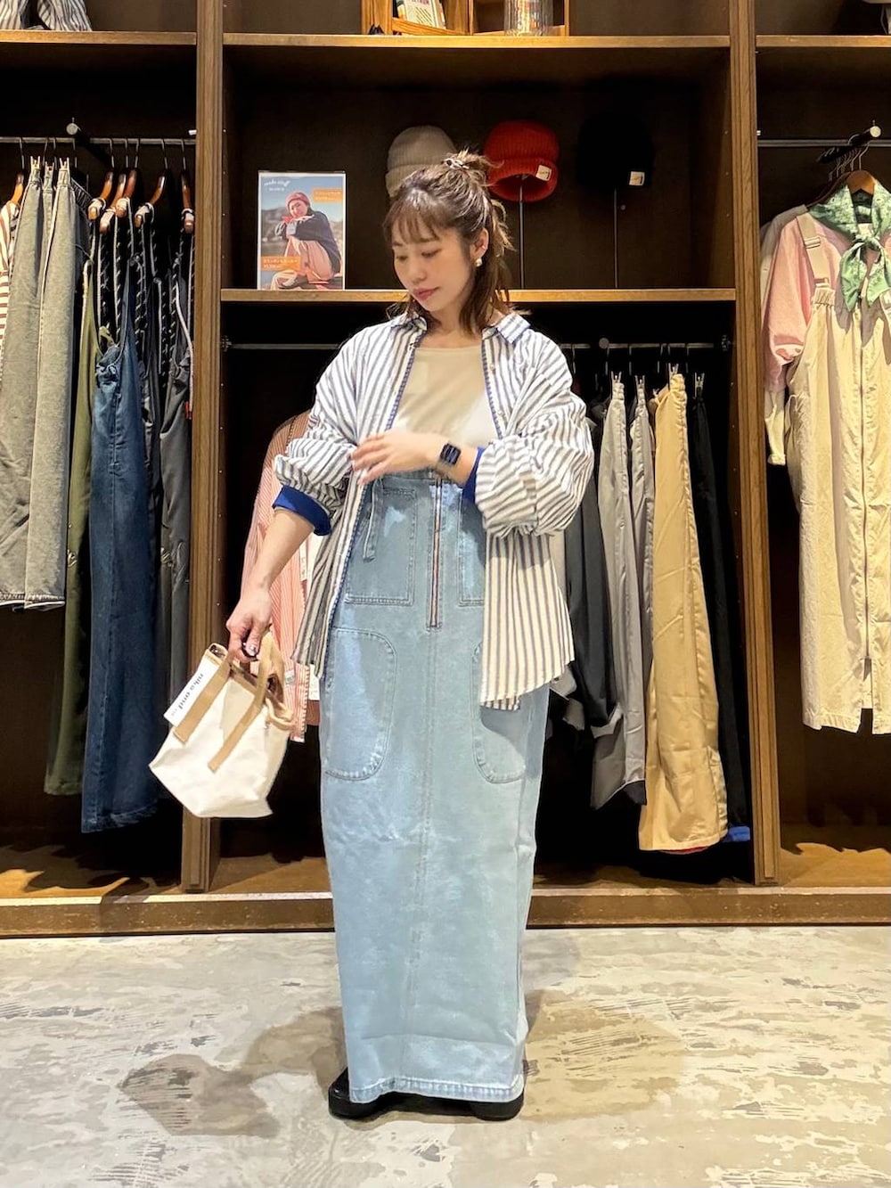 ブルー系のジャンパースカート、ベージュ系のTシャツ/カットソー、その他のショルダーバッグを着用したレディースの春コーディネートの3枚目の写真