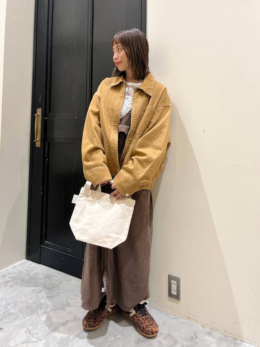 ブラウン系のジャンパースカート、ホワイト系のトートバッグ、ブラウン系のデニムジャケットを着用したレディースの春コーディネートの5枚目の写真