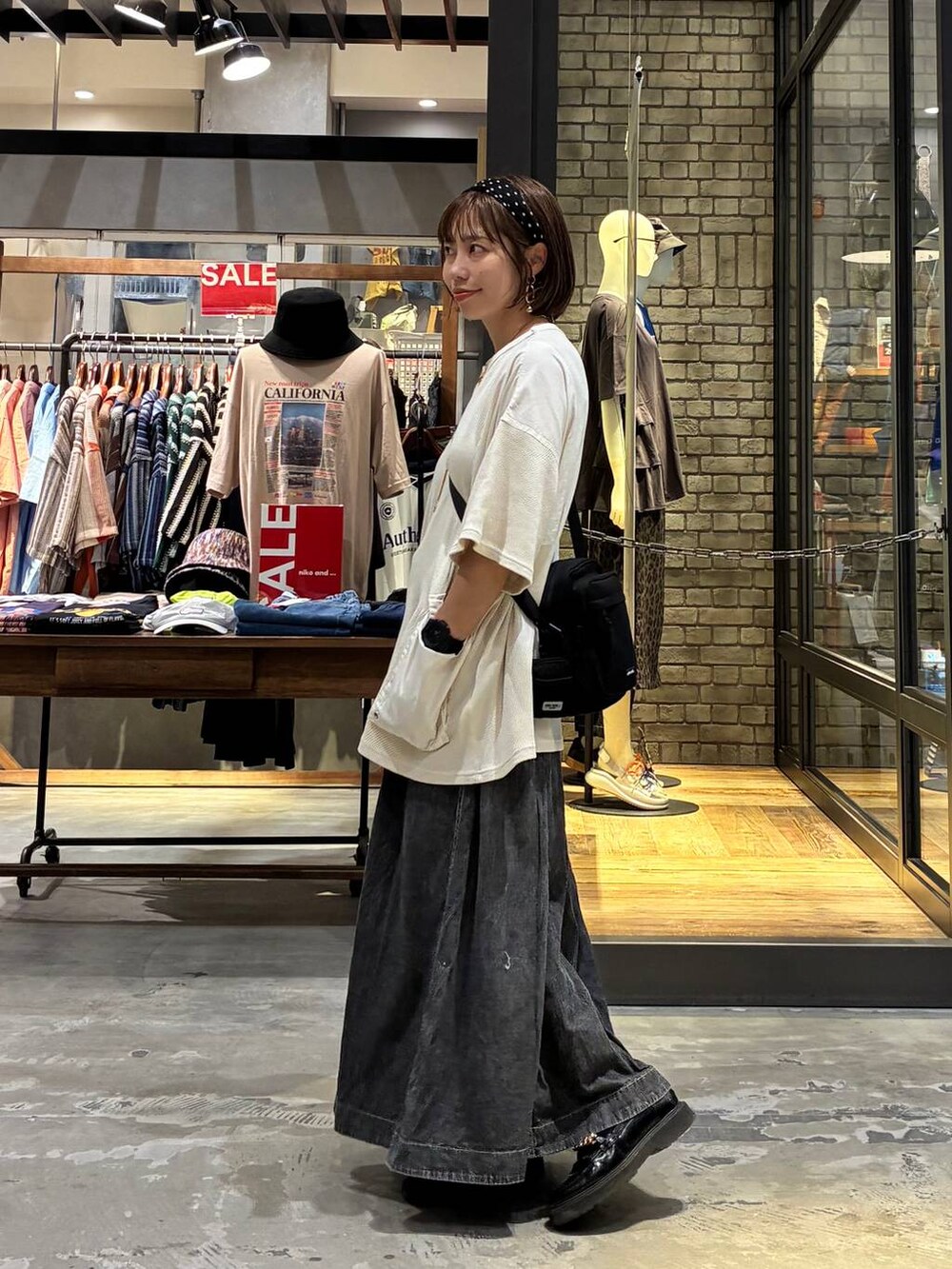 グレー系のスカート、ベージュ系のTシャツ/カットソー、ブラック系のショルダーバッグを着用したレディースの夏コーディネートの6枚目の写真