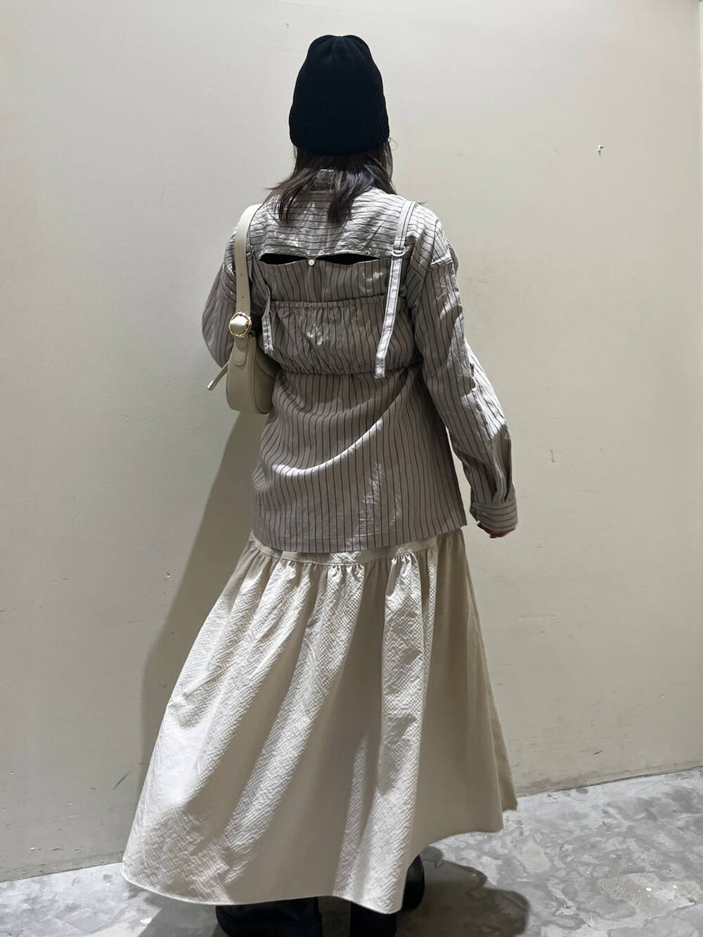 ベージュ系のショルダーバッグ、ブラック系のブーツ、ベージュ系のシャツ/ブラウスを着用したレディースの春コーディネートの3枚目の写真