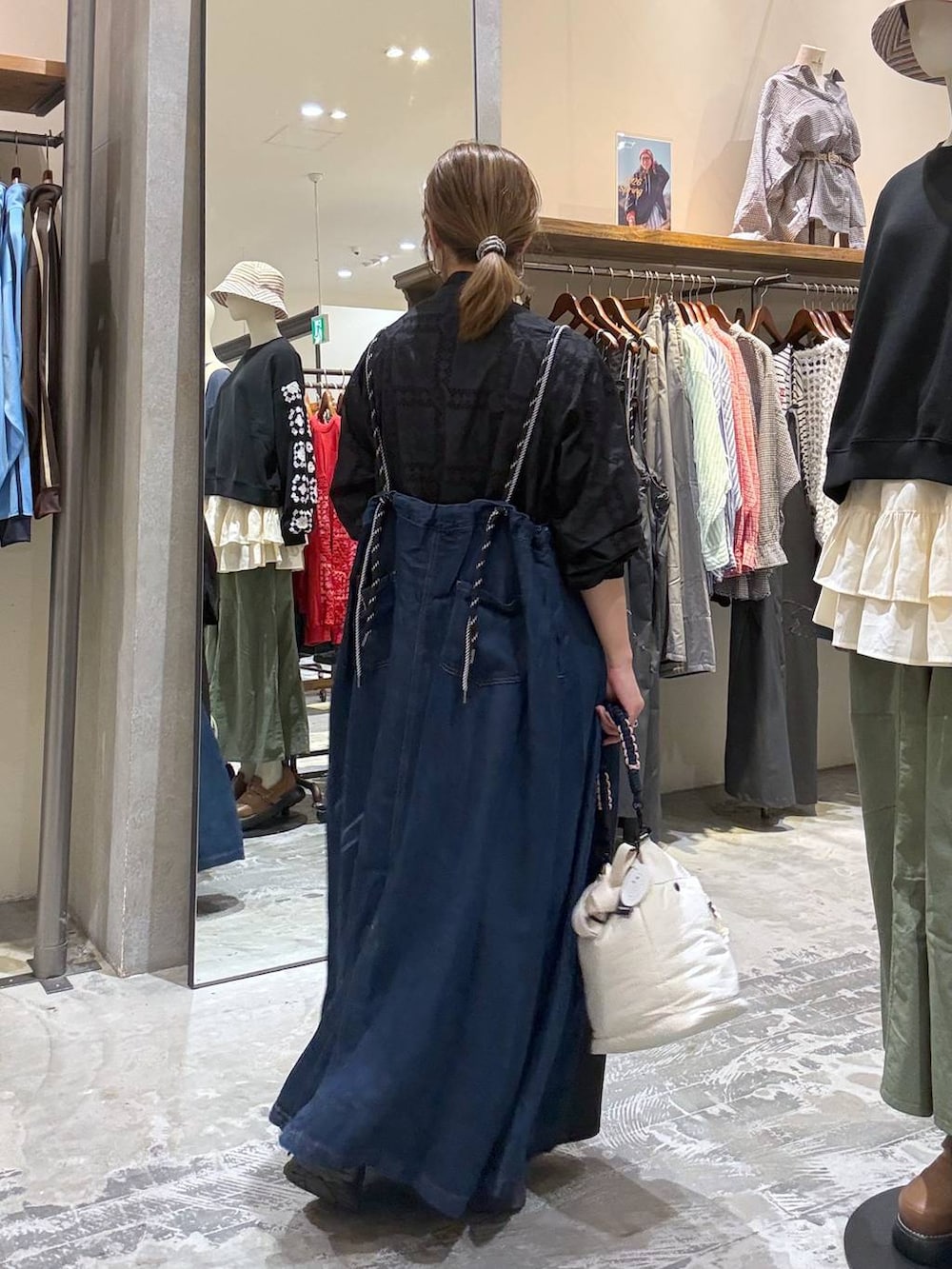 ブラック系のブルゾン、ブラック系のスカート、ベージュ系のショルダーバッグを着用したレディースの春コーディネートの2枚目の写真