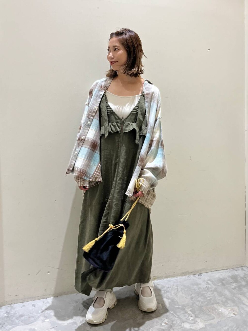 グリーン系のシャツ/ブラウス、グリーン系のジャンパースカート、ベージュ系のスニーカーを着用したレディースの秋コーディネートの3枚目の写真