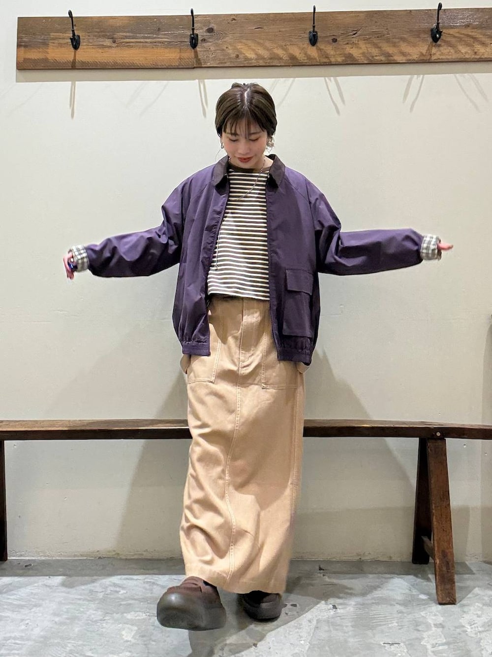 イエロー系のスカート、レッド系のブルゾン、ブラウン系のローファーを着用したレディースの春コーディネートの2枚目の写真