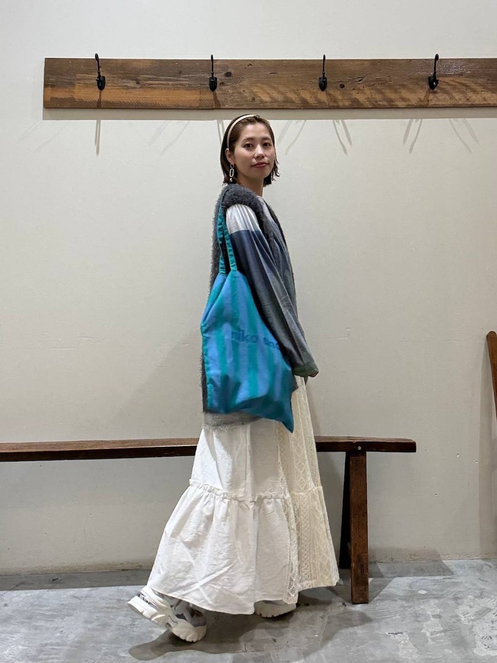 シルバー系のスニーカー、その他のトートバッグ、ベージュ系のスカートを着用したレディースの秋コーディネートの2枚目の写真