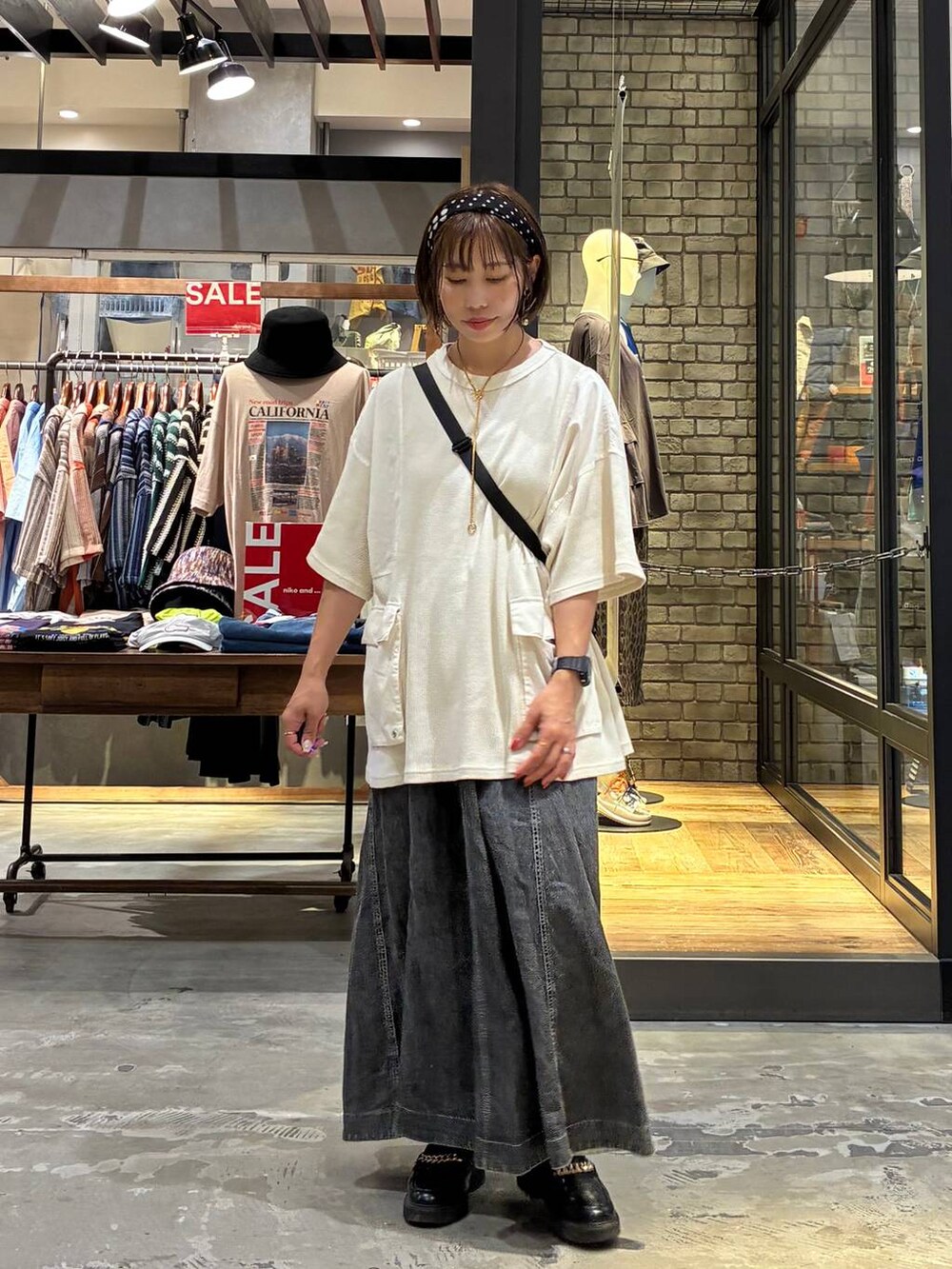 グレー系のスカート、ベージュ系のTシャツ/カットソー、ブラック系のショルダーバッグを着用したレディースの夏コーディネートの8枚目の写真