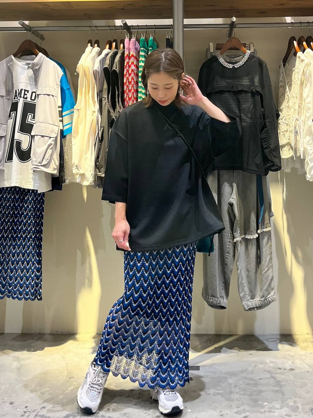 ブルー系のスカート、グレー系のスニーカー、ブルー系のショルダーバッグを着用したレディースの春コーディネートの2枚目の写真
