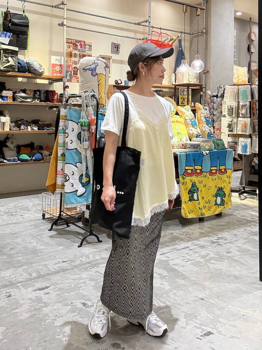 ブラック系のトートバッグ、ブラック系のスカート、ベージュ系のTシャツ/カットソーを着用したレディースの春コーディネートの4枚目の写真