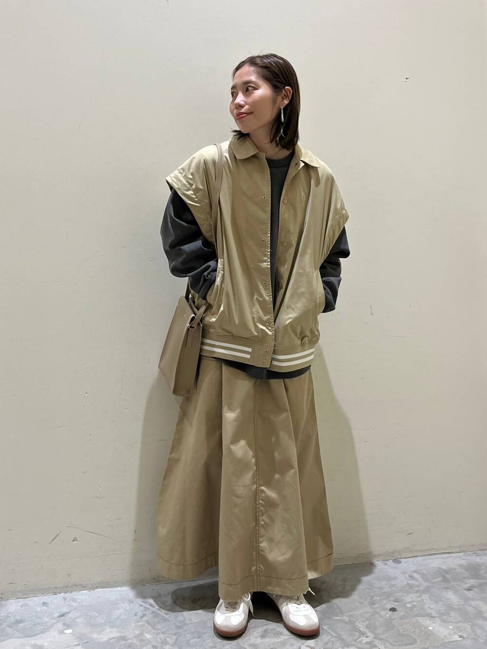 ベージュ系のスニーカー、ベージュ系のスタジャン、ベージュ系のスカートを着用したレディースの冬コーディネートの5枚目の写真