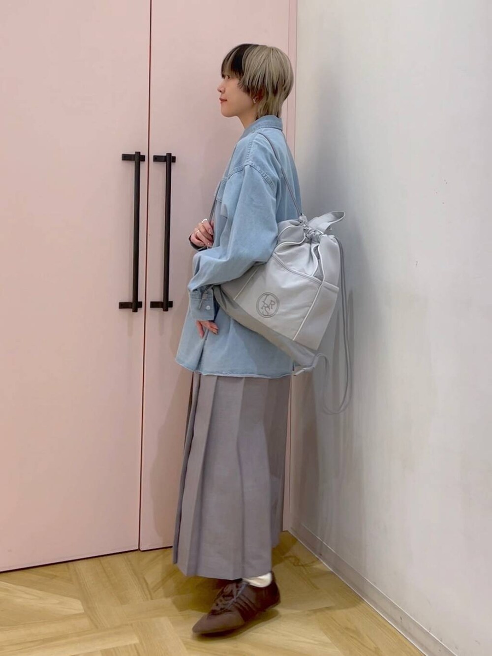 ブラウン系のスニーカー、グレー系のバックパック/リュック、ブルー系のシャツ/ブラウスを着用したレディースの冬コーディネートの2枚目の写真