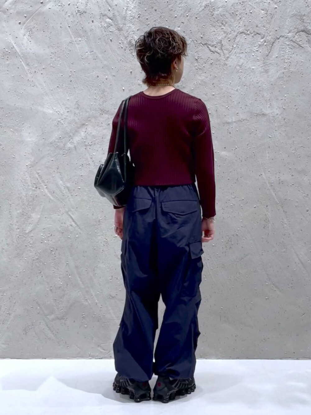 レッド系のカーディガン/ボレロ、ブルー系のカーゴパンツ、ブラック系のショルダーバッグを着用したレディースの秋コーディネートの3枚目の写真