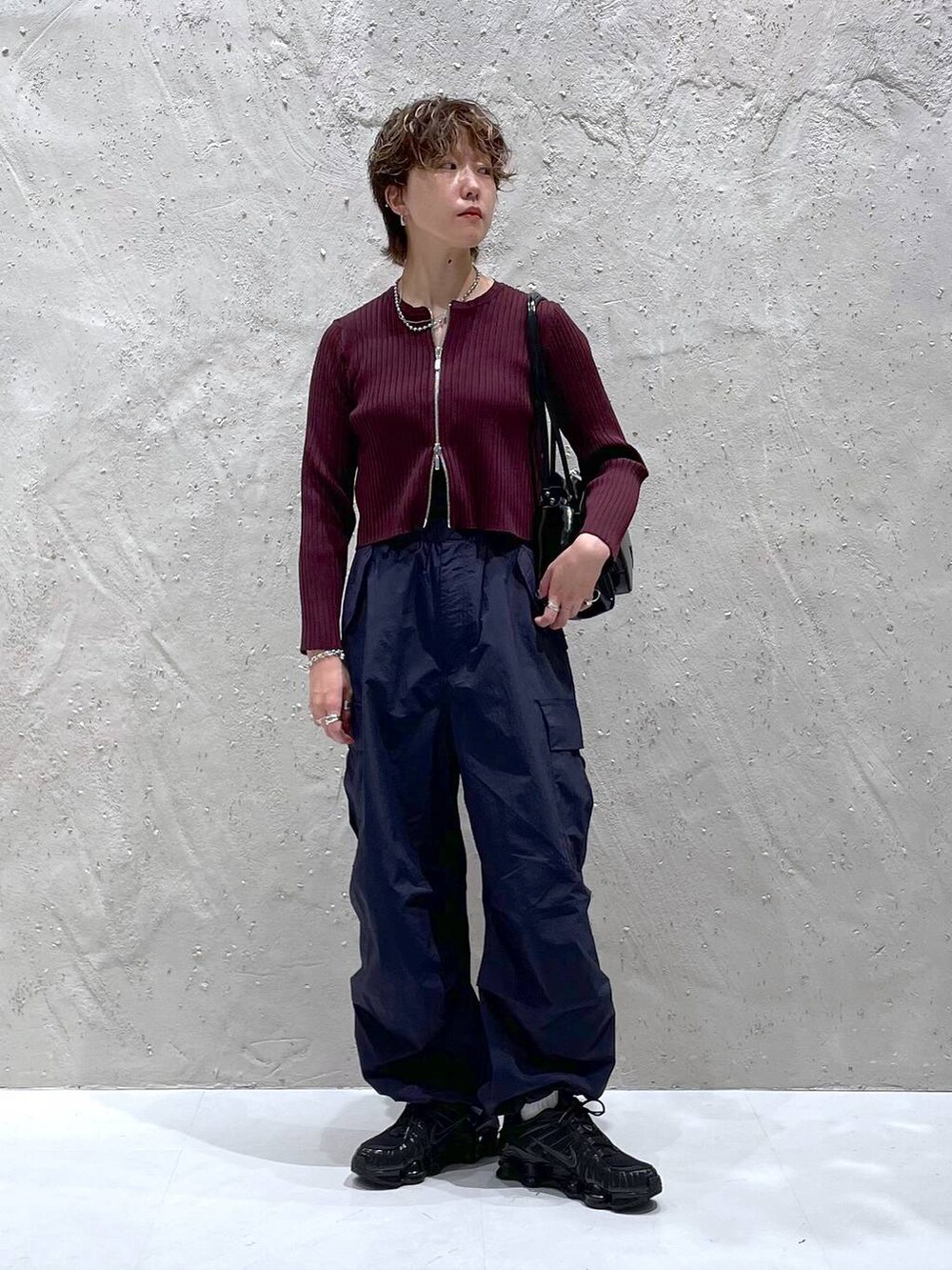 レッド系のカーディガン/ボレロ、ブルー系のカーゴパンツ、ブラック系のショルダーバッグを着用したレディースの秋コーディネートの5枚目の写真