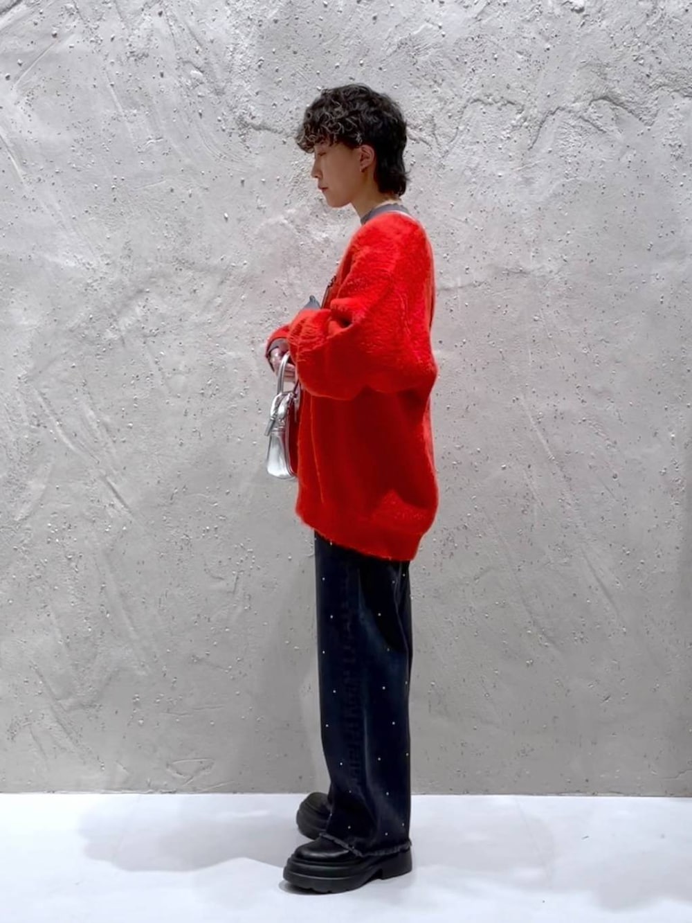 ブラック系のブーツ、シルバー系のボストンバッグ、オレンジ系のニット/セーターを着用したレディースの冬コーディネートの4枚目の写真