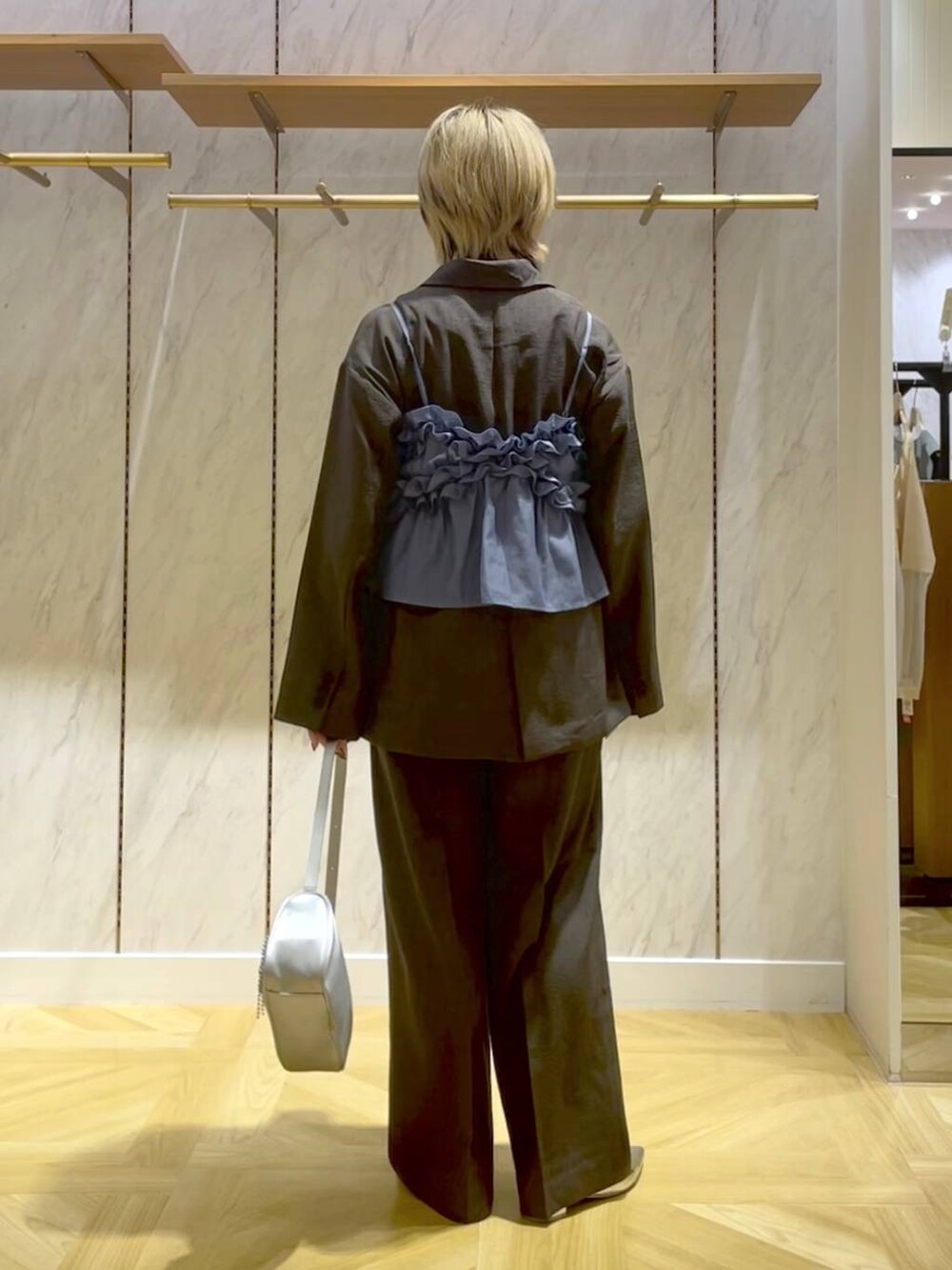 グレー系のスラックス、グレー系のテーラードジャケット、シルバー系のトートバッグを着用したレディースの春コーディネートの3枚目の写真