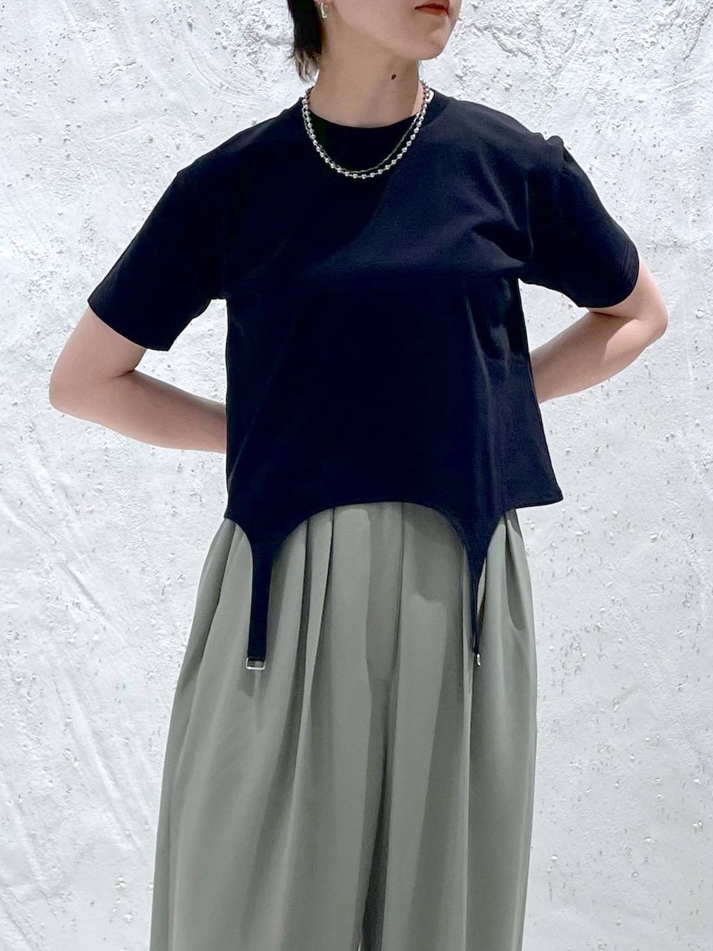 グリーン系のスラックス、ブラック系のTシャツ/カットソー、ブラック系のサンダルを着用したレディースの夏コーディネートの5枚目の写真