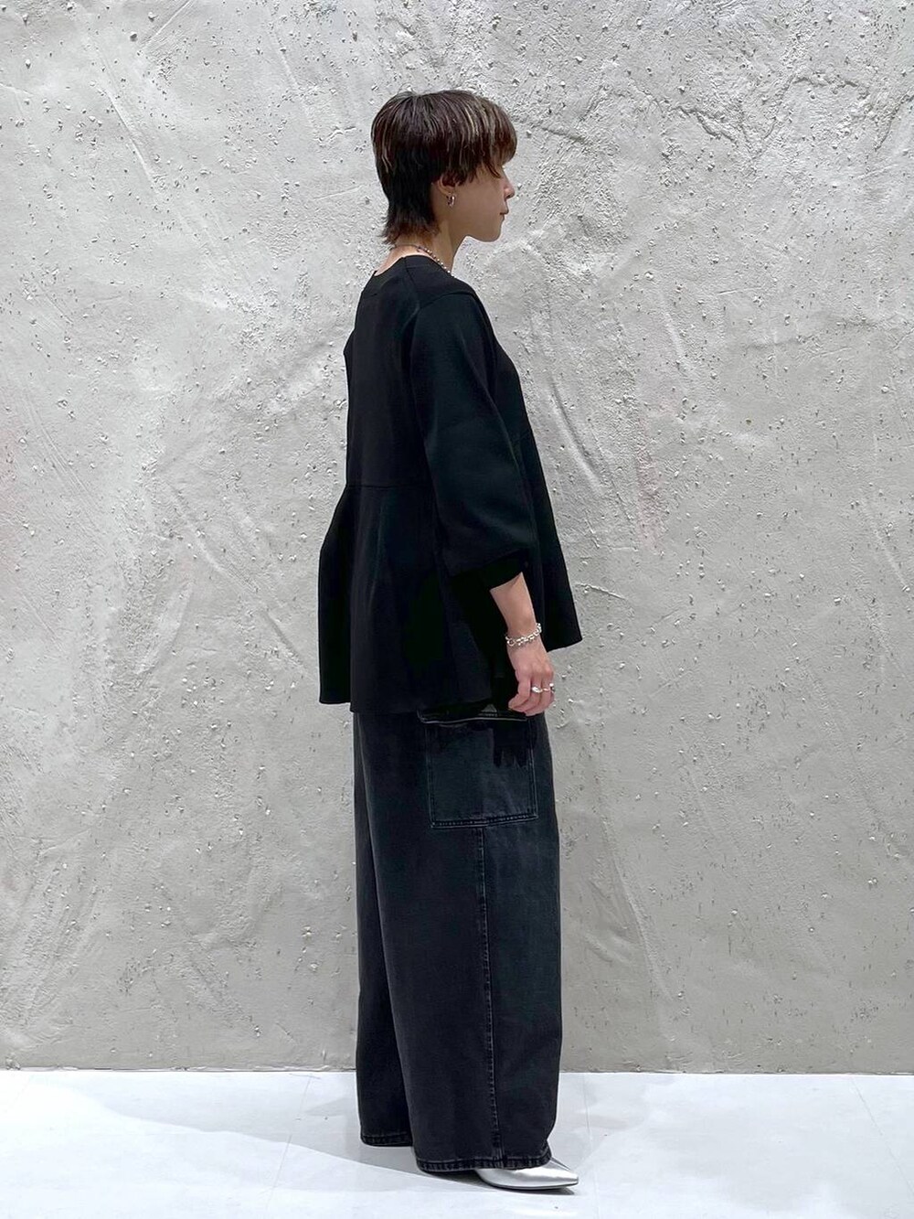 ブラック系のデニムパンツ、ブラック系のカーディガン/ボレロ、シルバー系のブーツを着用したレディースの秋コーディネートの2枚目の写真