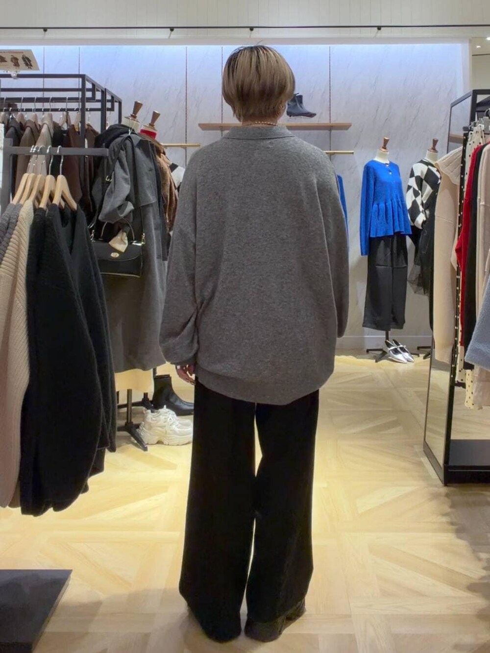 ブラック系のブーツ、グレー系のニット/セーター、ブラック系のスラックスを着用したレディースの秋コーディネートの2枚目の写真