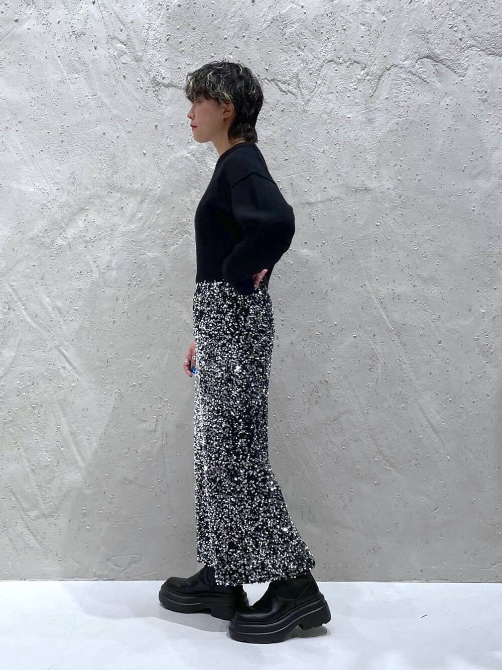 ブラック系のブーツ、ブラック系のニット/セーター、シルバー系のスカートを着用したレディースの秋コーディネートの4枚目の写真