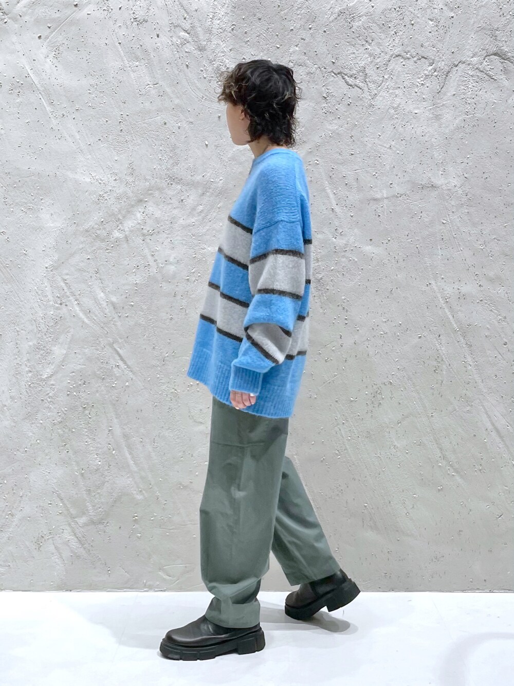 ブルー系のニット/セーター、ブラック系のブーツを着用したレディースの冬コーディネートの2枚目の写真