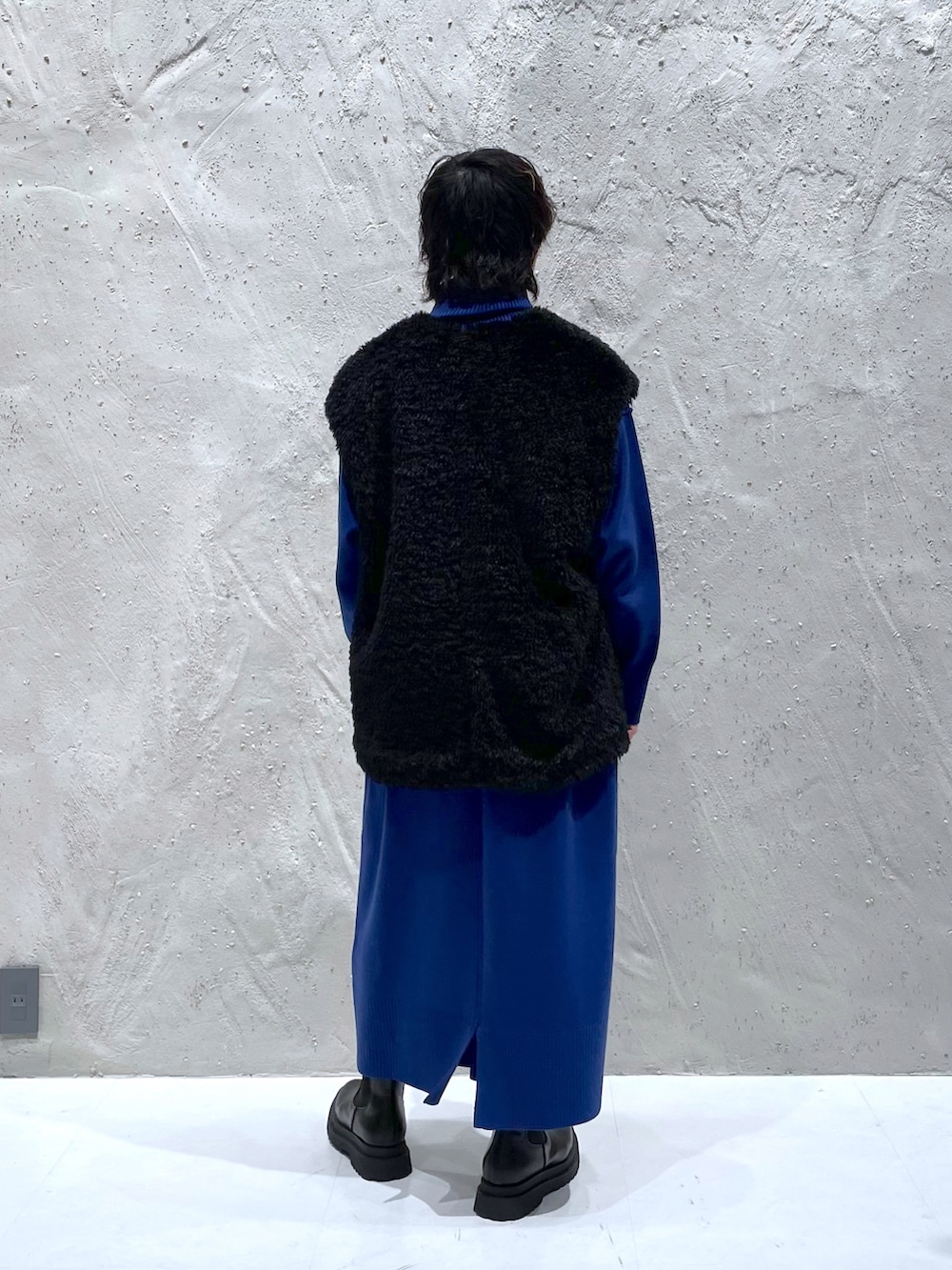 ブラック系のブルゾン、ブルー系のワンピース、ブラック系のブーツを着用したレディースの冬コーディネートの4枚目の写真