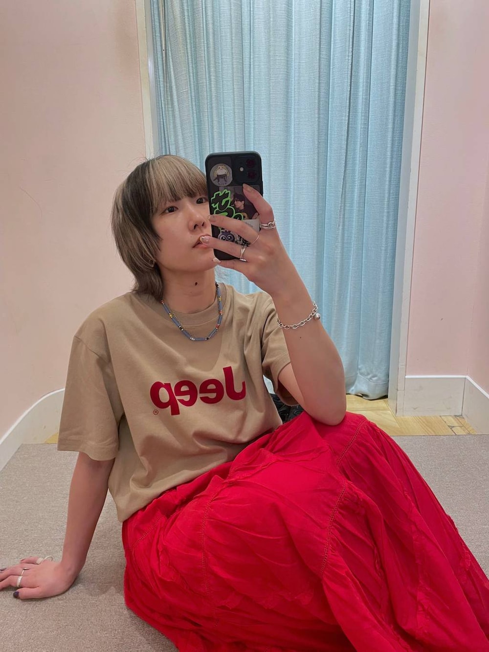 レッド系のスカート、ベージュ系のTシャツ/カットソーを着用したレディースの春コーディネートの2枚目の写真